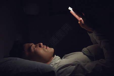 年轻男士深夜躺在床上玩手机高清图片下载-正版图片501698661-摄图网