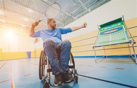 Adult man with a physical disability in a wheelchair playing tennis on ...