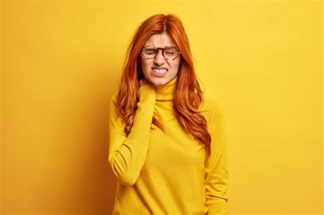 Redhead displeased woman touches neck feels strong pain has office ...