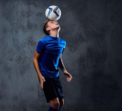 Blond teenager, soccer player dressed in a blue uniform plays with a ...