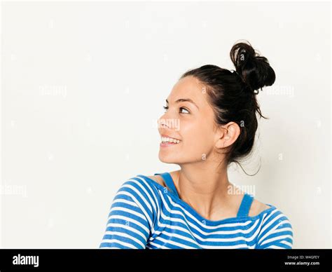 Beautiful young woman with black hair and blue white striped sweater is ...