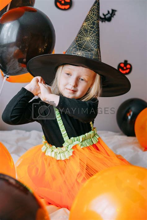 Children's Halloween - a girl in a witch hat and a carnival costume with airy orange and black ...