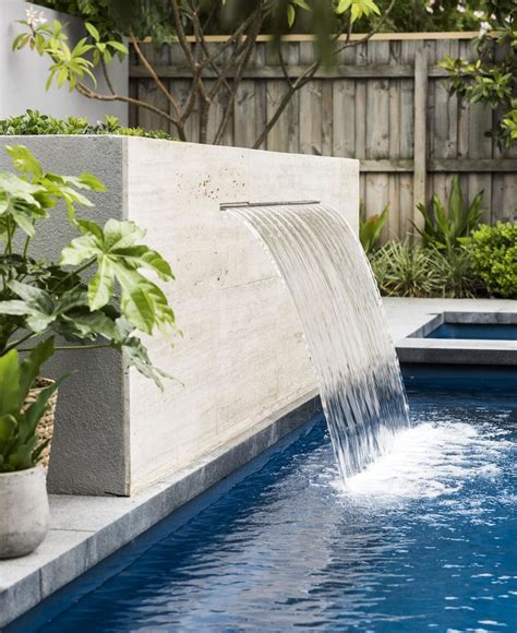 A travertine-clad water feature flows into the fibreglass swimming pool ...