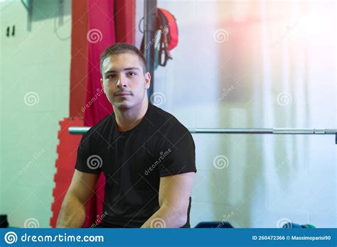 Athletic Young Man Poses Seated on the Bench Press Looking at the ...