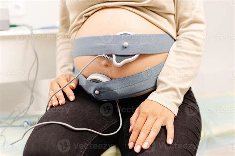 Woman pregnant checking fetal heart beat by fetal monitoring. Expectant mother with midwife ...