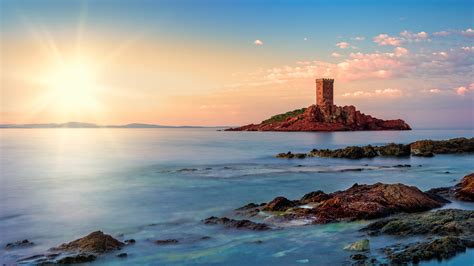 Download wallpaper the sun, rays, stones, castle, rocks, shore, tower ...