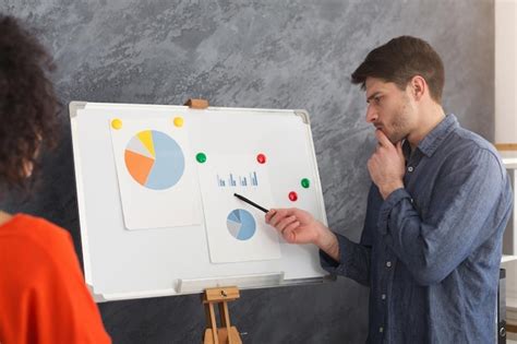 Young thoughtful businessman giving presentation to colleague in board ...