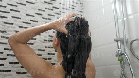 Young woman taking a shower and washing her hair in the bathroom ...