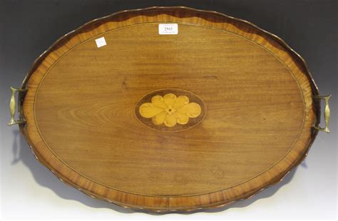 An Edwardian mahogany oval inlaid tray with a shaped gallery and brass ...