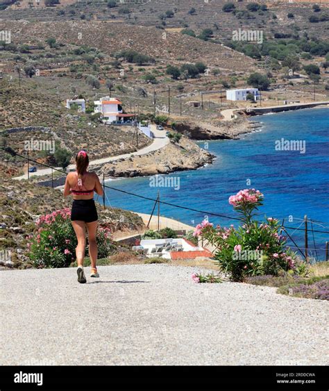 Young woman running down a steep road, hot weather, Tilos island, Dodecanese Greek island group ...