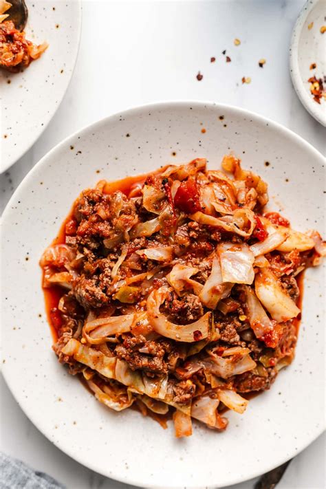 A skillet containing a dish with cooked cabbage ground meat and tomatoes resembling unstuffed cabbag