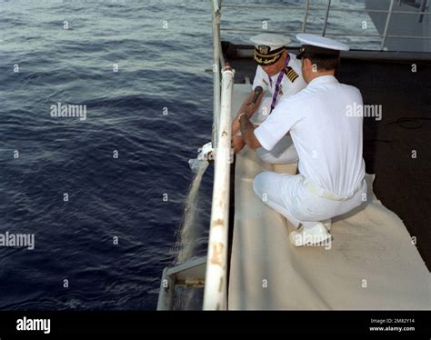 CAPT. Lester L. Westling, Chaplain Corps, is assisted by another ...
