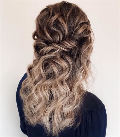 a woman with long wavy hair in a half updo hairstyle is shown from the back
