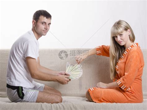夫妻坐在沙发上互相对质丈夫认为工资是收到的妻子抽一张钞票高清图片下载-正版图片306855486-摄图网