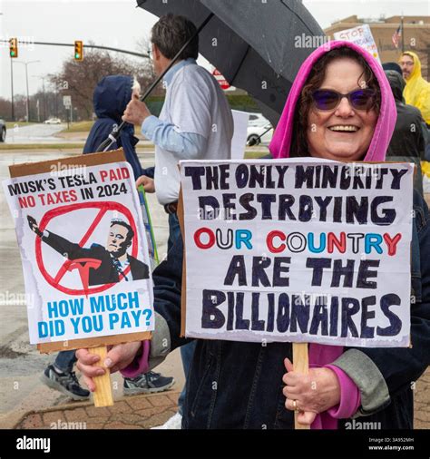 Troy, Michigan USA - 29 March 2025 - People gathered in the rain outside the Tesla Showroom at ...