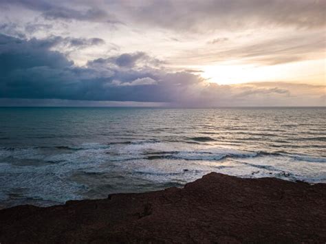 Sunrise in the ocean with blue and orange sky with dramatic clouds at ...