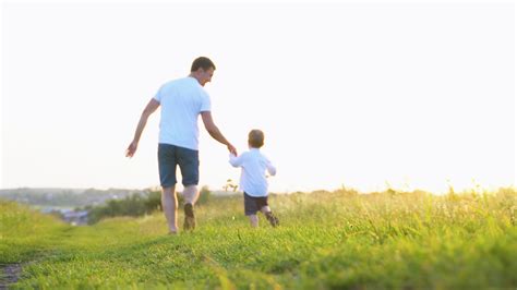 feliz pai e pequeno filho corre juntos dentro Sol dentro parque. feliz ...