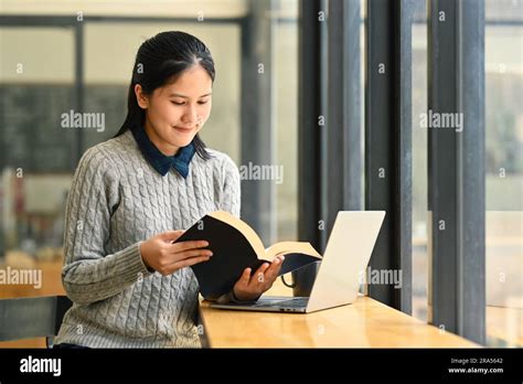 Positive asian woman reading novel or checking his working schedule ...