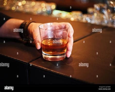 Male hand holds a glass of whiskey on the bar counter Stock Photo - Alamy