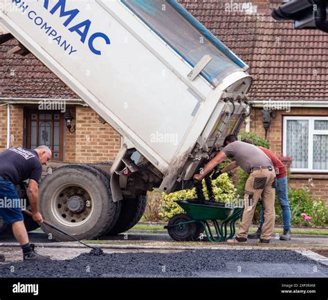 Construction workers are using a truck to lay asphalt on a residential ...