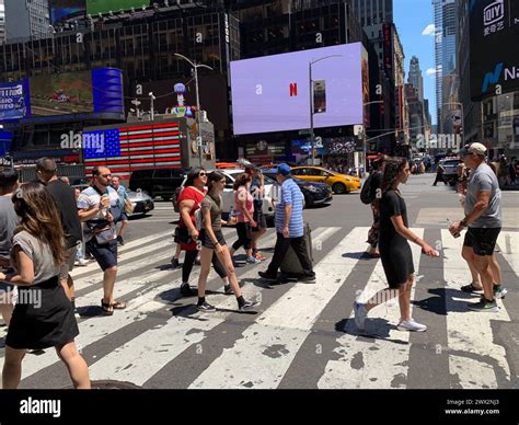 Pedestrians are surrounded by video billboards as they cross the street ...