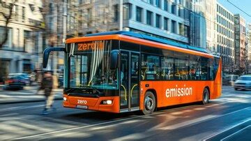 An electric bus with a zero emission logo driving through a city center ...