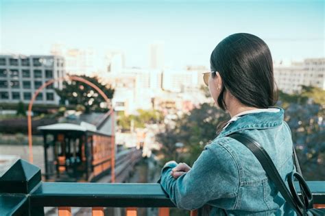 Back view of young asian girl leaning on rail looking at angels flight ...