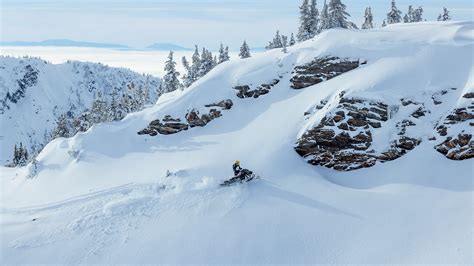 Rider riding up a snowy mountain on the 2027 Ski-Doo Summit