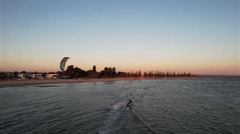 Drone following kite surfer from behind on a flat ocean as the sunsets ...