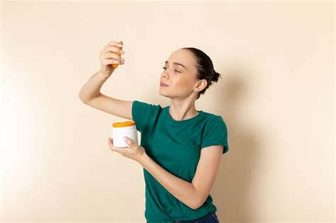 Front view young female in dark green shirt and blue jeans holding can ...