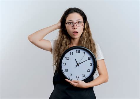 Young professional hairdresser woman in apron holding wall clock ...
