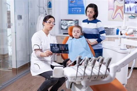 Cheerful little girl sitting in dental office while doctor showing ...