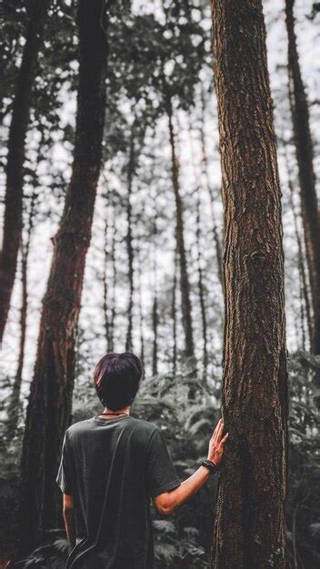 Rear view of man standing by tree trunk in forest | Premium Photo