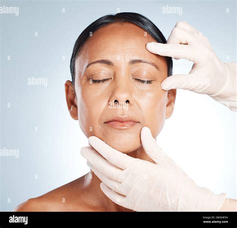 Botox, mature woman and doctor hands check face for plastic surgery and beauty consultation ...