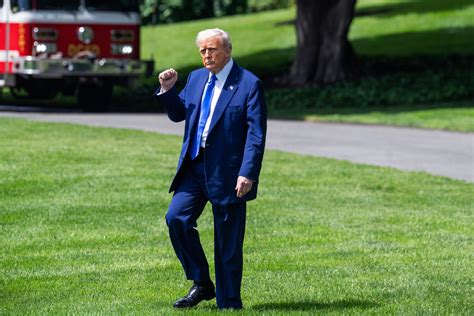 A banner showing an image of President Donald Trump is seen behind an American flag outside a US Dep Minimalist