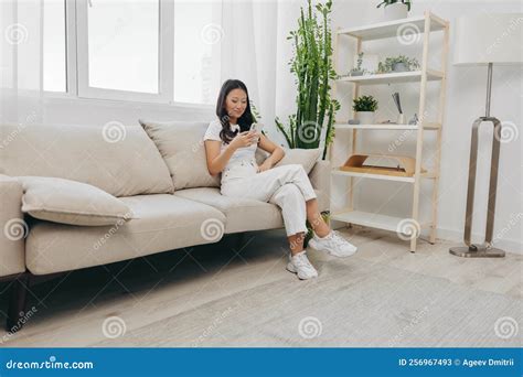 Young Asian Woman Smiling Sitting at Home on the Couch Relaxing and ...