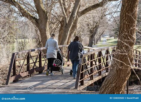 Two Young Moms Pushing Strollers in Park in Early Spring Stock Photo ...