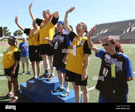Competitors from a 100 meter dash wave to the crowd at the award stands ...