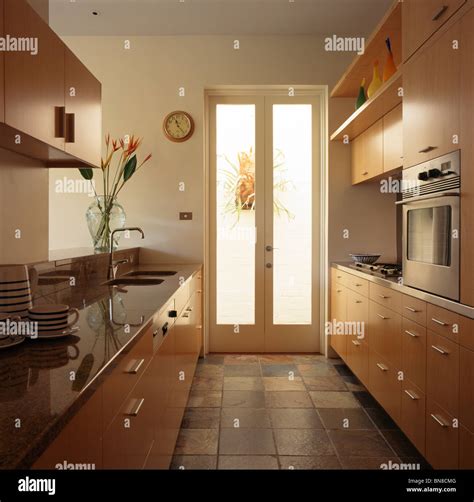 Slate floor tiles and glass double doors in galley kitchen with pale ...