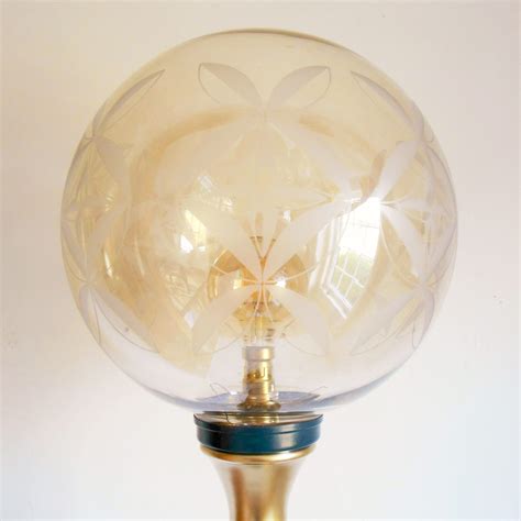 A gold and navy floor lamp with a vintage glass globe shade ...