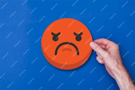Männliche Hand, die ein unglückliches Smiley-Kopfsymbol des Emoji ...