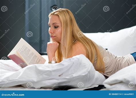 Woman reading in The Ritz-Carlton bed at a hotel