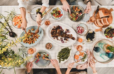 家人，朋友聚餐平躺的人手在桌子上烤羊肩，沙拉，蔬菜，小吃，玫瑰酒和米莫萨树枝，顶视图。庆祝派对晚宴高清摄影大图-千库网
