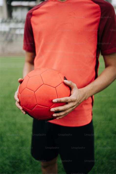 A red soccer ball sitting on top of a soccer field photo – Sport Image ...
