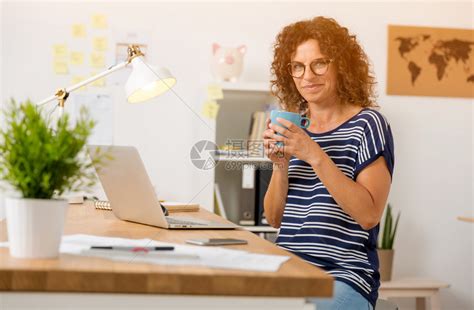 中年妇女在办公室喝热咖啡的中年妇女商业电脑设计师高清图片下载-正版图片307876419-摄图网