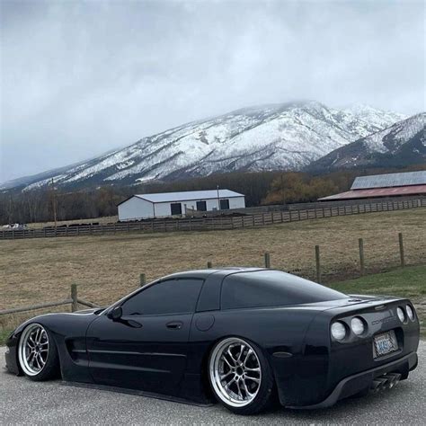 Black Corvette parked in front of mountains