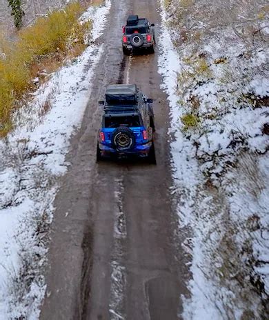 A Ford Bronco SUV, with available roof rack, is parked on a snowy road ...