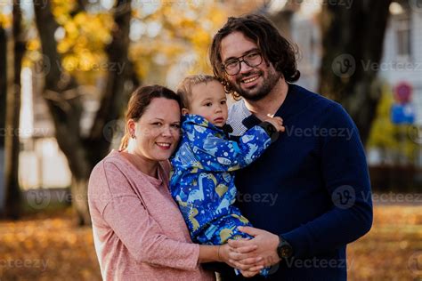en un soleado otoño día en el parque, un madre y padre cariñosamente ...