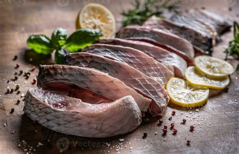 Portioned fish carp with salt pepper lemon and herbs on kitchen board ...