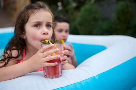 Focus on a glass with fresh fruit juice in the hands of blurred child ...
